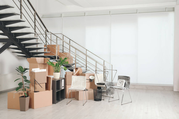 Cardboard boxes and packed stuff near stairs in office, space for text. Moving day - Фото, изображение