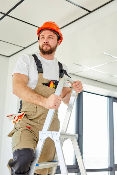 Confident professional repairman contractor working on overhead ceiling panel - Foto, immagini