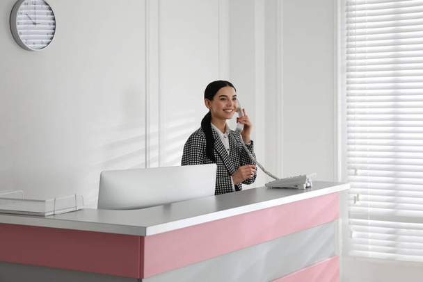 Администратор разговаривает по телефону на прилавке в офисе - Фото, изображение