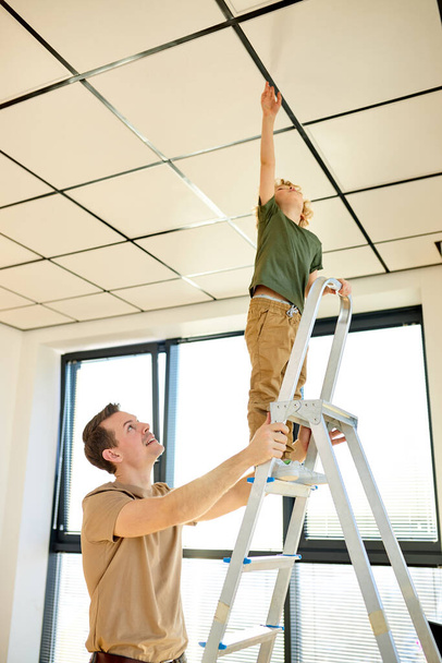 Happy family renovating home, painting ceiling together in new apartment - 写真・画像