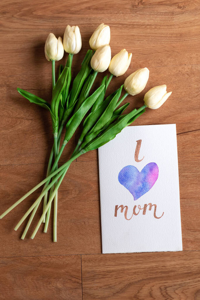 Watercolour card with i love mom word and flower on wooden floor - Fotoğraf, Görsel