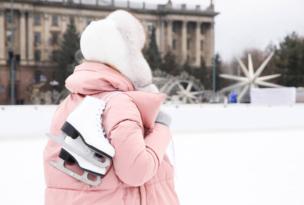 Woman with figure skates near ice rink outdoors. Space for text - Photo, Image