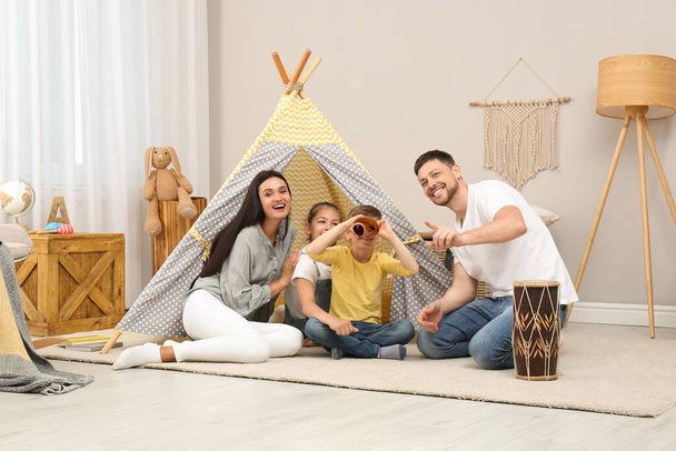 Happy family with treasure map near toy wigwam at home - Foto, Imagen
