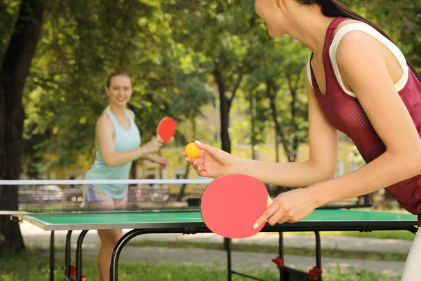 Young women playing ping pong in park, closeup - 写真・画像