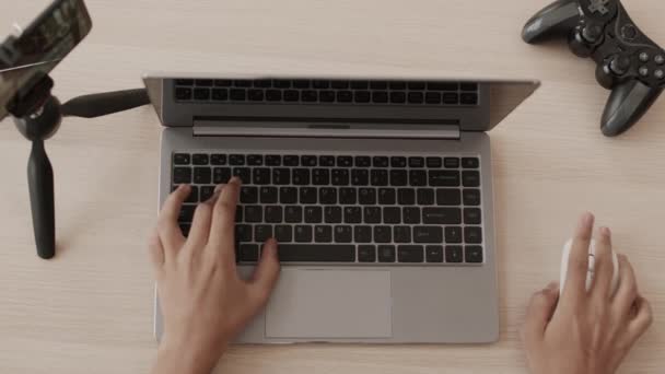 Vue du dessus des mains d'un joueur méconnaissable jouant sur un ordinateur portable en appuyant sur les boutons du clavier, en utilisant la souris au bureau - Séquence, vidéo