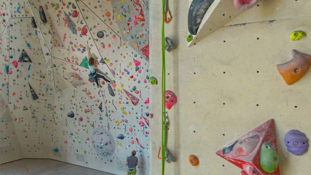 DRONE: Competitive rock-climber trains indoors with her coach belaying her. - Photo, Image