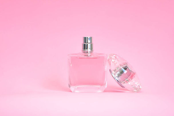 elegant perfume bottle with open lid on pink pastel background - Foto, Imagem