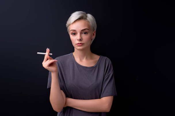 Confident woman holding Cigarette in hands. Cigarettes or tobacco, isolated on black - Φωτογραφία, εικόνα