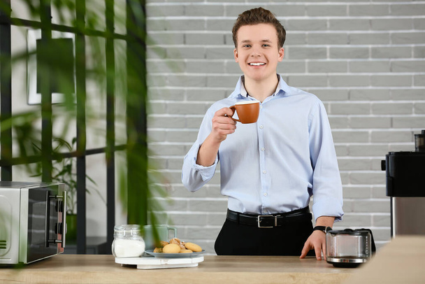 Young man drinking coffee in office - Fotoğraf, Görsel