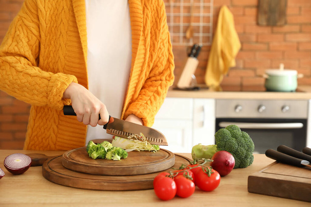 Женщина режет капусту на кухне - Фото, изображение