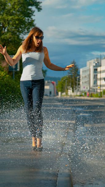 Vrouw is geschokt als ze wordt bespat met water door zorgeloze bestuurder - Foto, afbeelding
