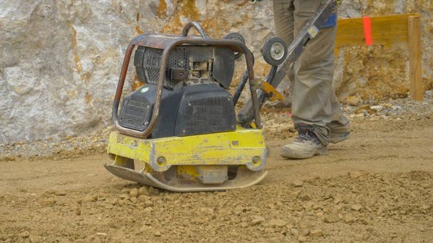 FECHAR-se O homem usa a máquina de nivelamento manual para preparar o solo para o derramamento de argamassa - Foto, Imagem