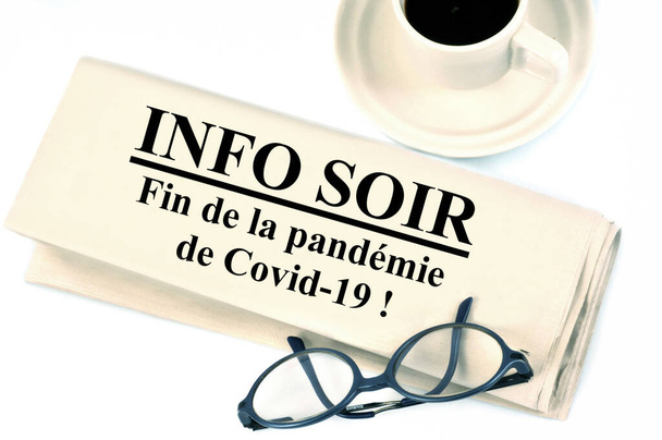Newspaper concept announcing in french the end of the Covid-19 pandemic next to a cup of coffee and glasses on a white background  - Photo, Image