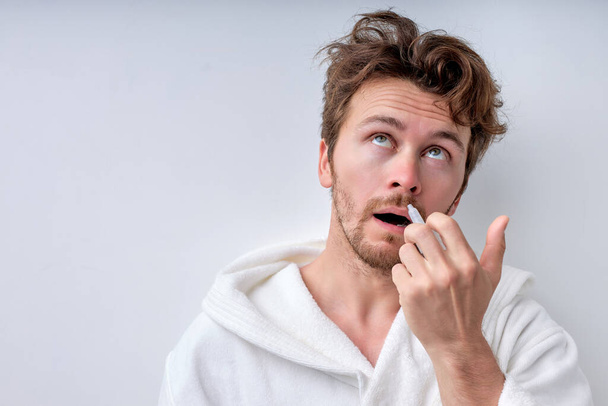 Portrait of attractive guy with nasal spray using nose drops over background - Фото, изображение
