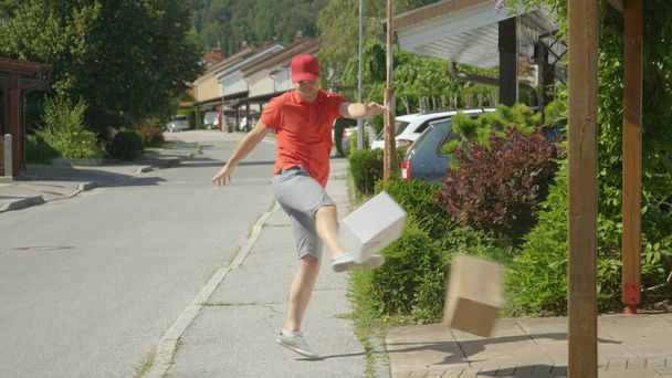 Rude millennial courier making his round around the suburbs kicks three parcels - Photo, Image