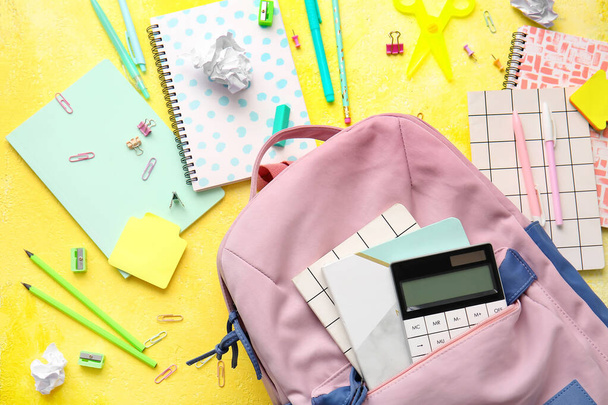 Шкільний рюкзак та канцелярські товари на кольоровому фоні
 - Фото, зображення