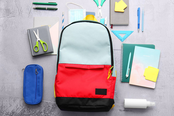 Шкільний рюкзак та канцелярські товари на світлому фоні
 - Фото, зображення
