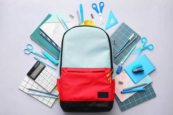 Шкільний рюкзак та канцелярські товари на світлому фоні
 - Фото, зображення