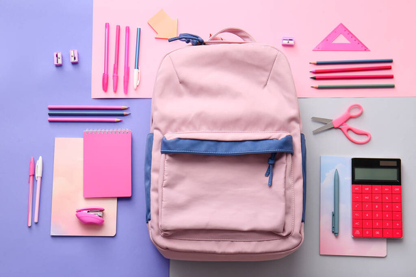 School backpack and stationery on color background - 写真・画像