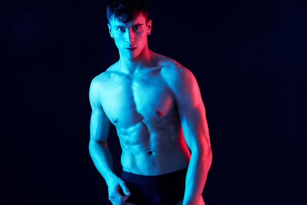 portrait of an attractive guy with a pumped-up torso bodybuilder black background  - Foto, Imagen