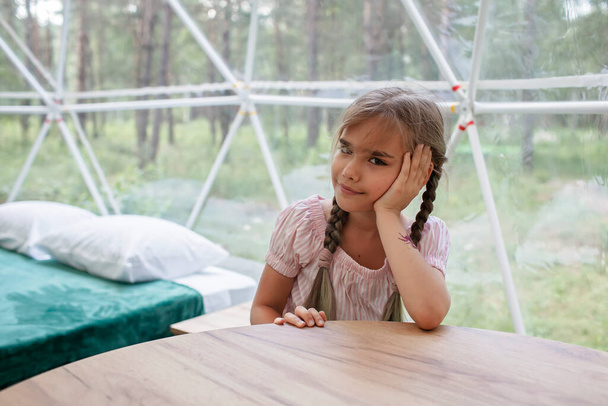 Fille regarde au-dessus de tente cloche transparente dans la forêt, glamping, voyage de luxe, camping glamour - Photo, image
