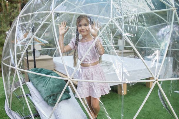 Mädchen blickt über transparentes Glockenzelt im Wald, Glamping, Luxusreisen, glamouröses Campen - Foto, Bild