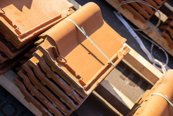 Stacks of yellow ceramic roofing tiles for covering residential building roof under construction. - Photo, Image