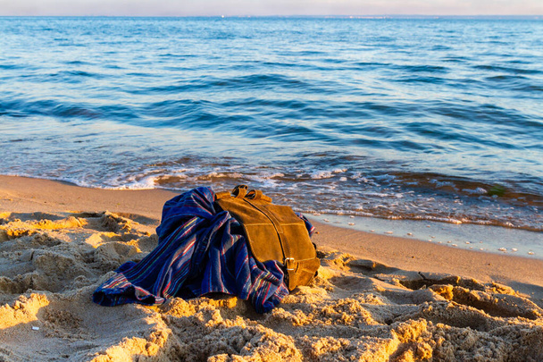 Matka- ja lomakonsepti. Tyhjä hiekkaranta auringonlaskun aikaan. Tyylikäs ruskea reppu matkustaja meren rannalla. Itämeri, Hel, Pommeri, Puola - Valokuva, kuva