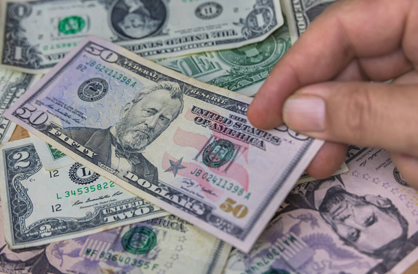 Amerika Birleşik Devletleri para birimi olan bir Amerikan dolarını elinde tutan bir erkek. Amerika 'nın Kağıt Parası' nı kapat. Dolar dünya para birimidir. Yaşlı adamın elleri en değerli parayı gösteriyor. 50 Grant  - Fotoğraf, Görsel