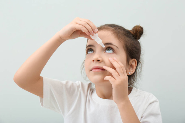 Adorable little girl using eye drops on white background - Fotografie, Obrázek