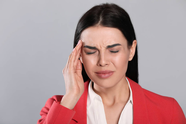 Woman suffering from migraine on grey background - Photo, Image