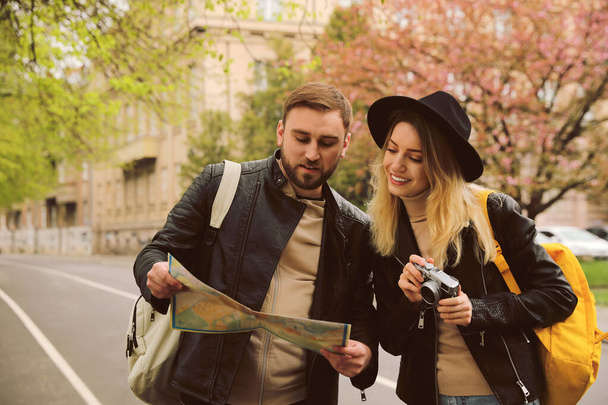 Couple of tourists with map and camera on city street - 写真・画像