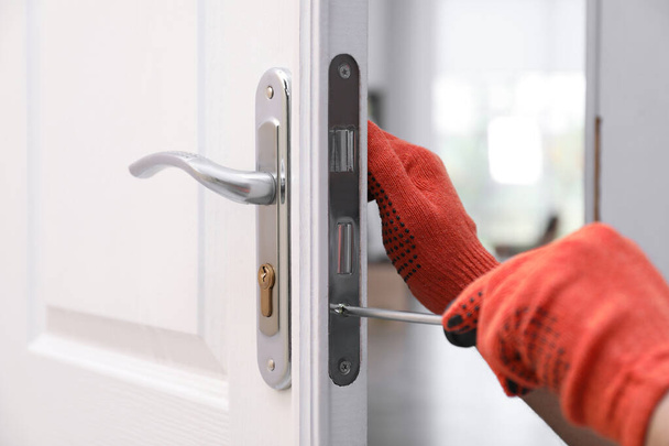 Handyman met schroevendraaier reparerend deurslot binnen, close-up - Foto, afbeelding
