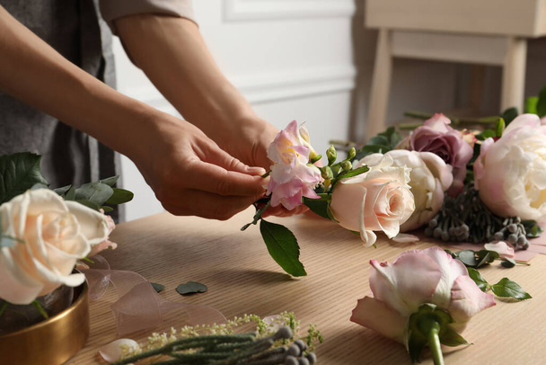Florist creating beautiful bouquet at wooden table indoors, closeup - Foto, imagen