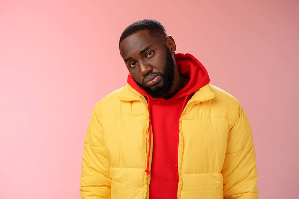 Unimpressed bored ignorant young african bearded man tilt head look scorn uninterest camera listen boring useless information, standing careless in yellow jacket red hoodie, indifferent - Photo, Image