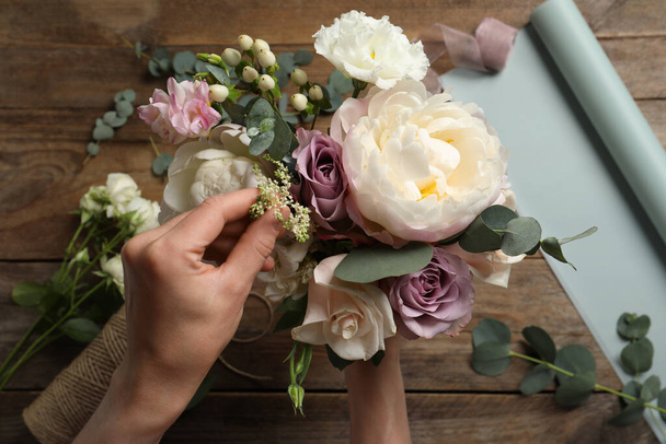 Florist creating beautiful bouquet at table, top view - Foto, imagen