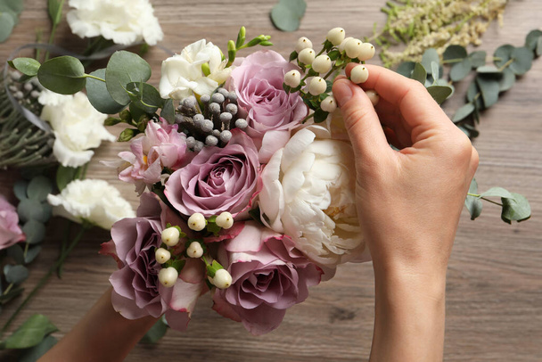 Florist creating beautiful bouquet at wooden table, closeup - Foto, imagen