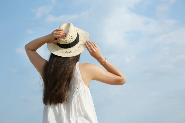 Beautiful young woman wearing straw hat outdoors, back view. Stylish headdress - Foto, Imagem
