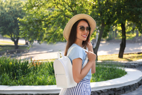 Beautiful young woman with stylish backpack in city park - Foto, afbeelding