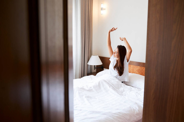 Mujer joven estirándose en la cama - Foto, Imagen