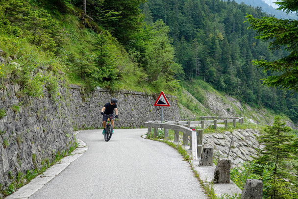 Мужской туристический педаль электрический велосипед вверх по крутой дороге в словенских горах. - Фото, изображение