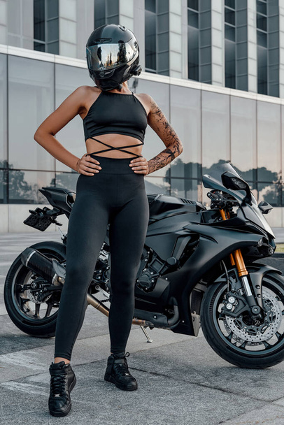 Front view shot of tattooed woman and black motorbike - Foto, Bild