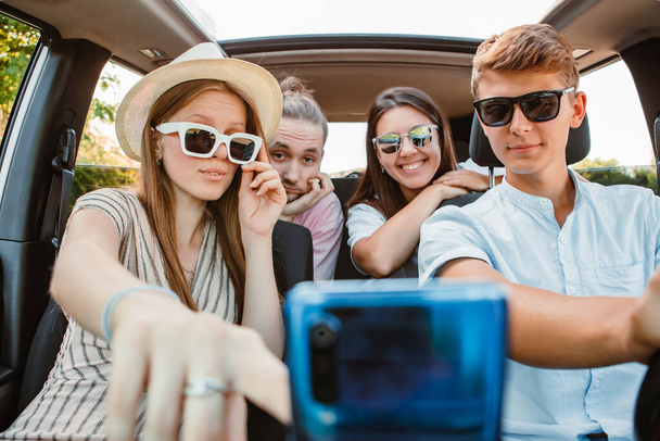 four friends in car navigation on phone. road trip - Foto, imagen