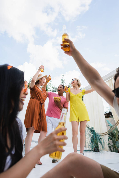 alegres amigos multiculturales brindando con cerveza durante la fiesta de verano en el patio - Foto, Imagen