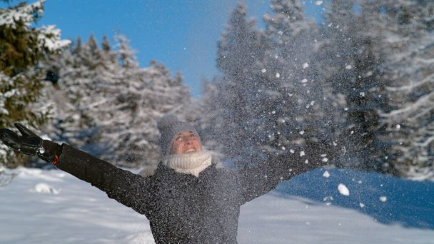 Nah dran: Jubelnde Touristin wirft eine Handvoll Neuschnee in die Luft. - Foto, Bild