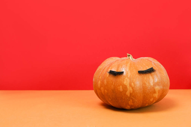 Halloween pumpkin with false eyelashes on red. Minimal Holiday season concept background. - Zdjęcie, obraz