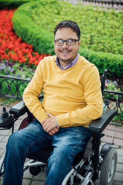 um homem com deficiência em uma cadeira de rodas andando olha para a vista - Foto, Imagem