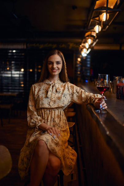 Alone woman with glass of wine sitting in bar - Фото, изображение