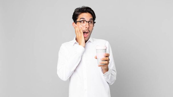 young hispanic man feeling happy, excited and surprised and holding a take away coffee - Valokuva, kuva