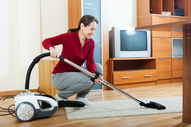 Mature woman with vacuum cleaner - Foto, afbeelding